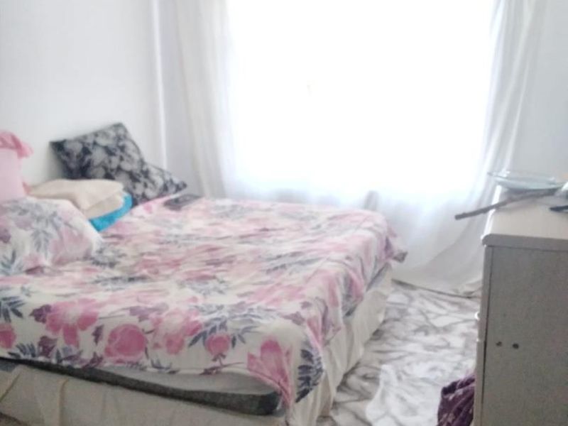 A bedroom featuring a large window allowing natural light, with dated flooring finishes throughout the space.