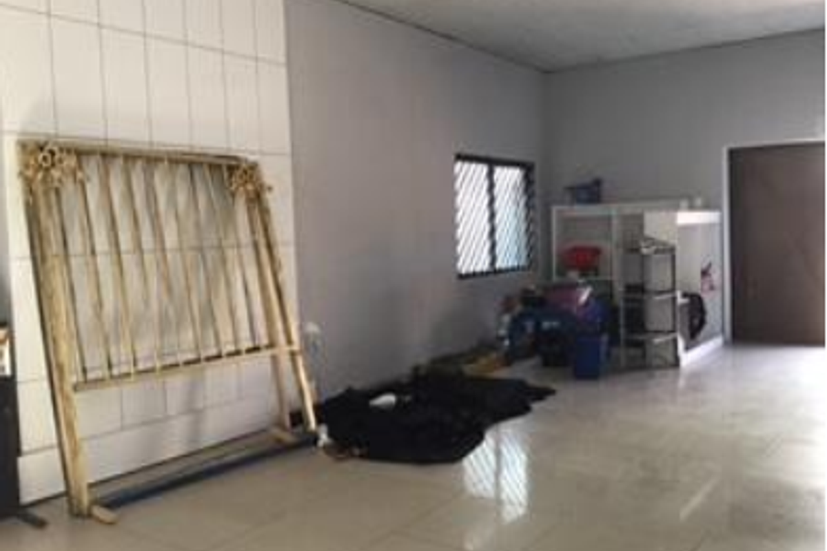 A functional utility space featuring tiled flooring, a suspended ceiling, and a window with security bars, offering a blank canvas for various commercial uses.