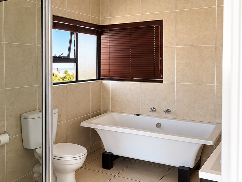 A clean, well-maintained bathroom featuring a freestanding bathtub, a separate glass-enclosed shower, and neutral floor-to-ceiling tiling.