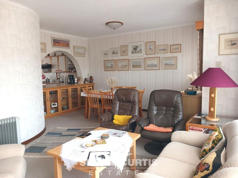 Open plan living and dining area featuring a semi-enclosed kitchen with built-in cabinetry and a distinctive architectural archway.
