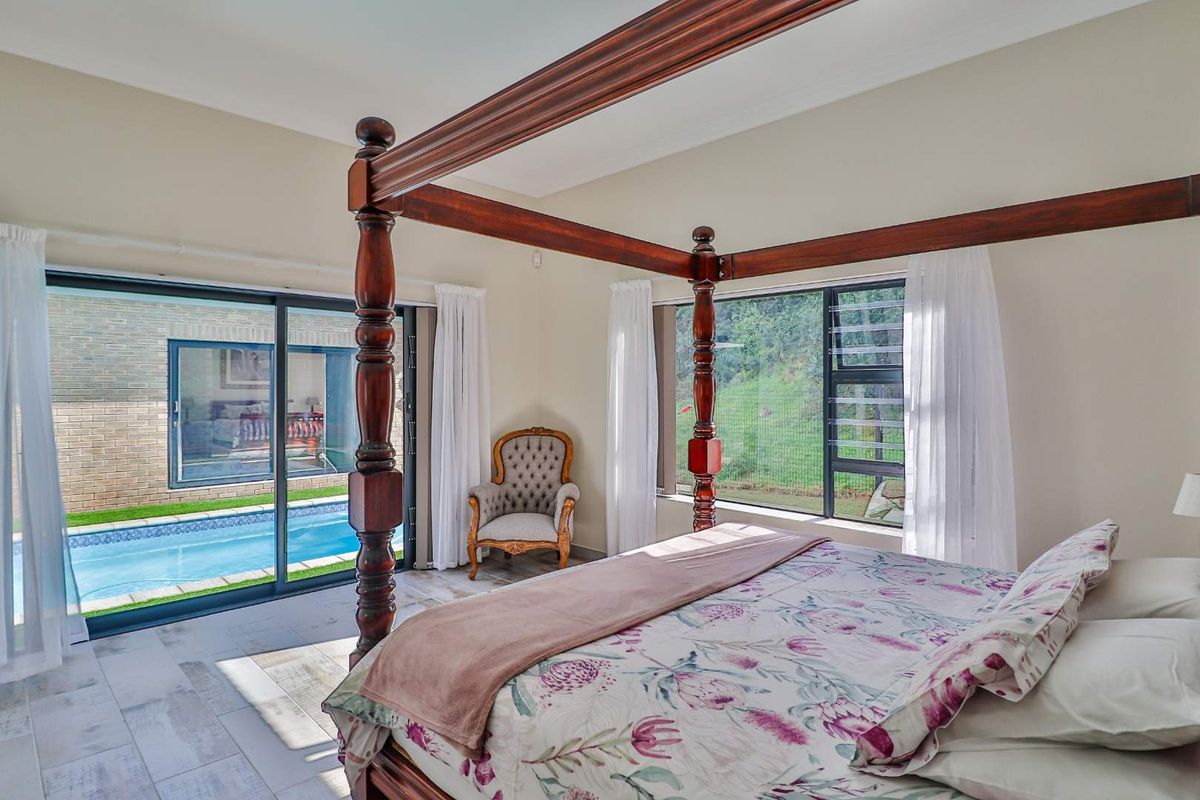 Spacious bedroom featuring large sliding glass doors that open directly onto a private swimming pool area, offering natural light and garden views.