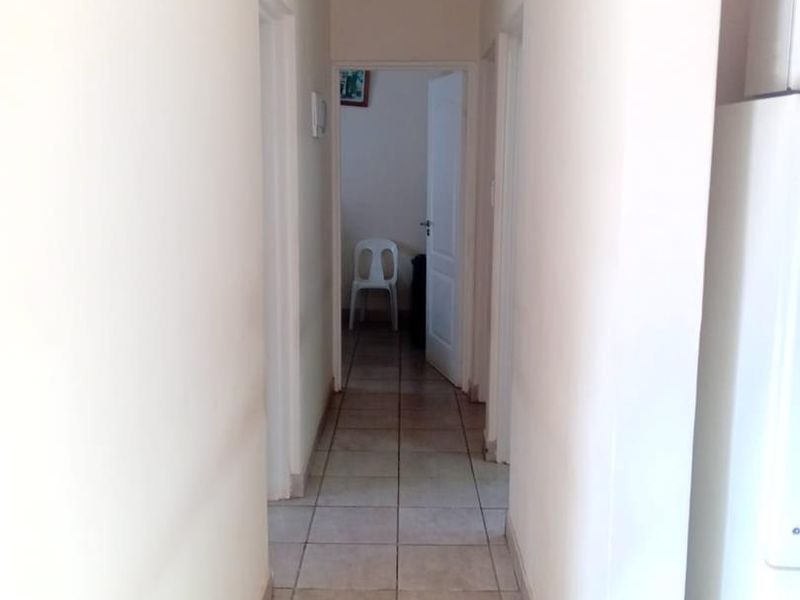 A functional hallway featuring neutral tiled flooring and access to adjacent rooms, providing a clean and simple transition space within the home.
