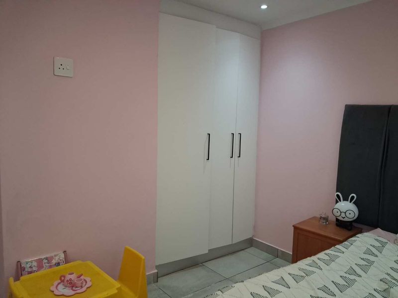 A bedroom featuring built-in white wardrobes, tiled flooring, and recessed ceiling lighting.