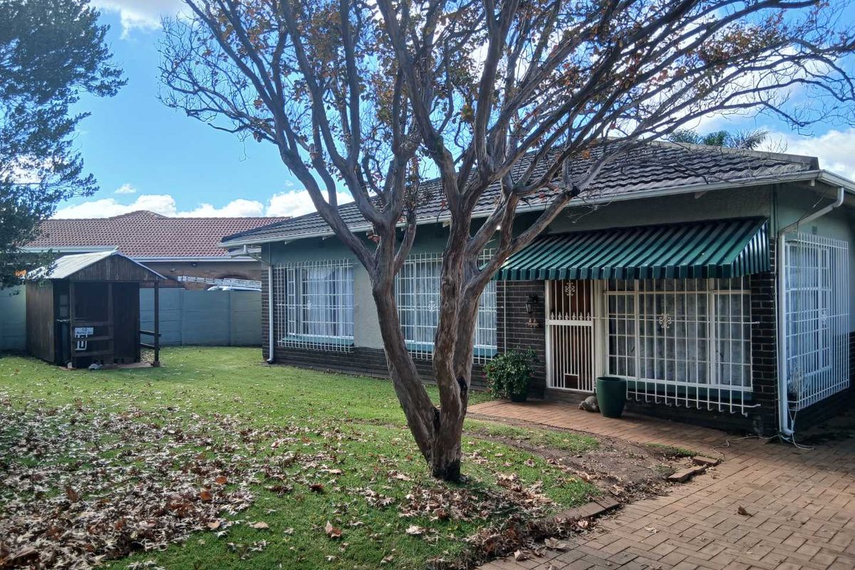Rear view of the house featuring a paved patio area, established garden, and a small detached wooden storage structure.