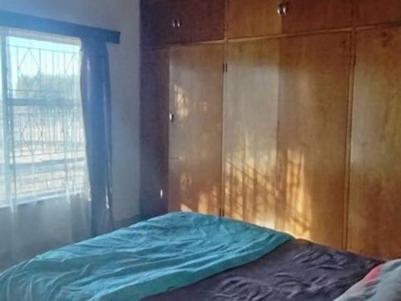 Bedroom featuring built-in wooden cupboards and a timber-clad ceiling with exposed beams, offering a dated aesthetic with potential for modernization.