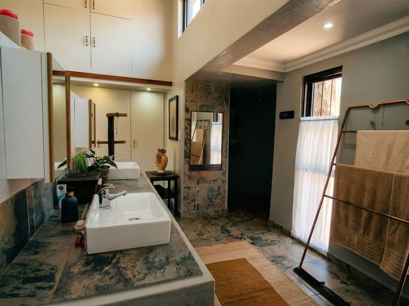 A spacious bathroom featuring a double vanity with vessel sinks, tiled countertops, ample built-in cabinetry, and tiled flooring with recessed lighting.