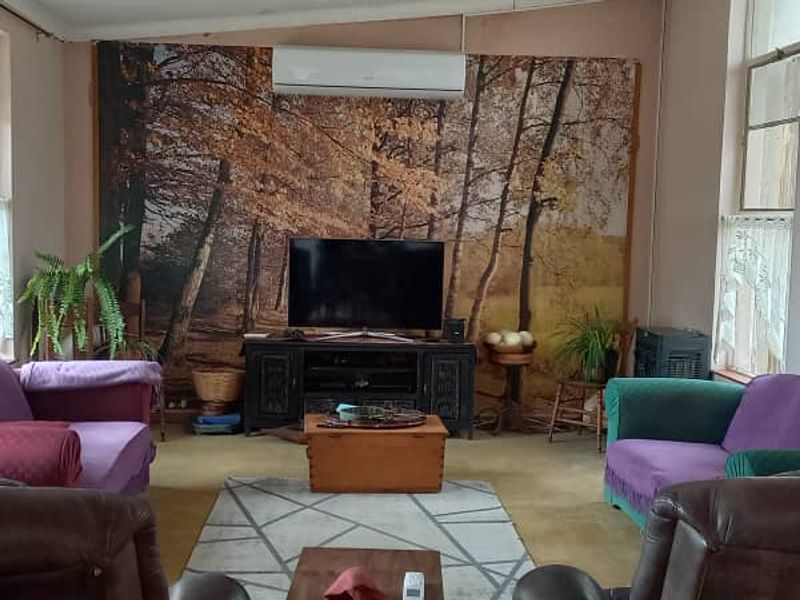 A spacious living room featuring a wall-mounted split-system air conditioner and large windows providing natural light.
