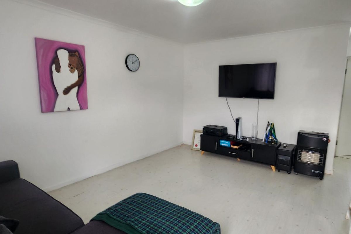 A functional living room area featuring neutral white walls, coved ceilings, and light-toned laminate flooring, providing a blank canvas for interior design updates.