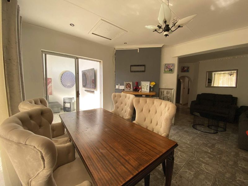 Open plan dining and living area featuring tiled flooring, a sliding glass door leading to an outdoor space, and an arched transition to the lounge.