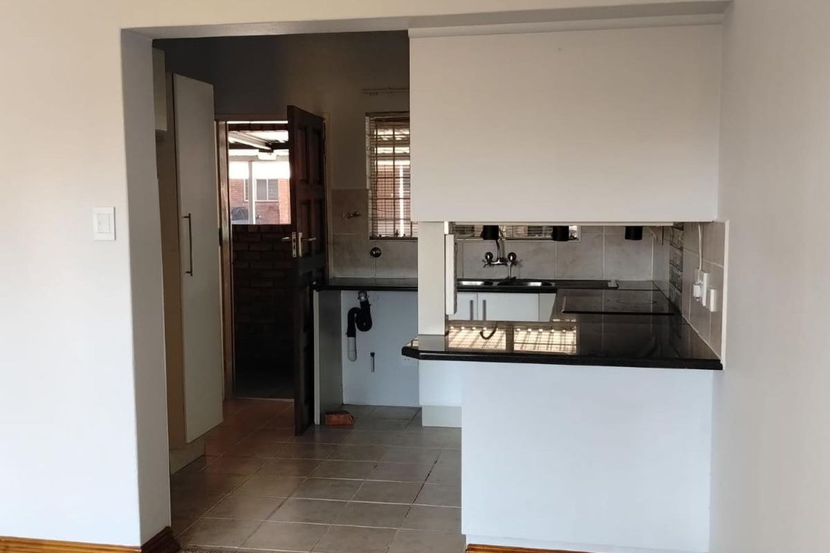A compact kitchen featuring granite countertops, tiled flooring, and built-in cabinetry, currently requiring minor repairs to plumbing and cabinetry finishes.