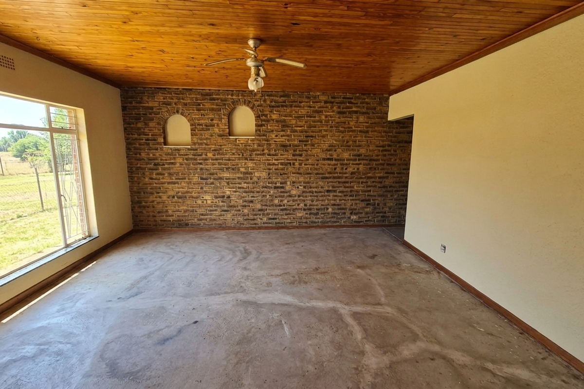 Spacious living area featuring a rustic exposed brick feature wall with arched niches, a timber-clad ceiling, and large windows overlooking the garden.