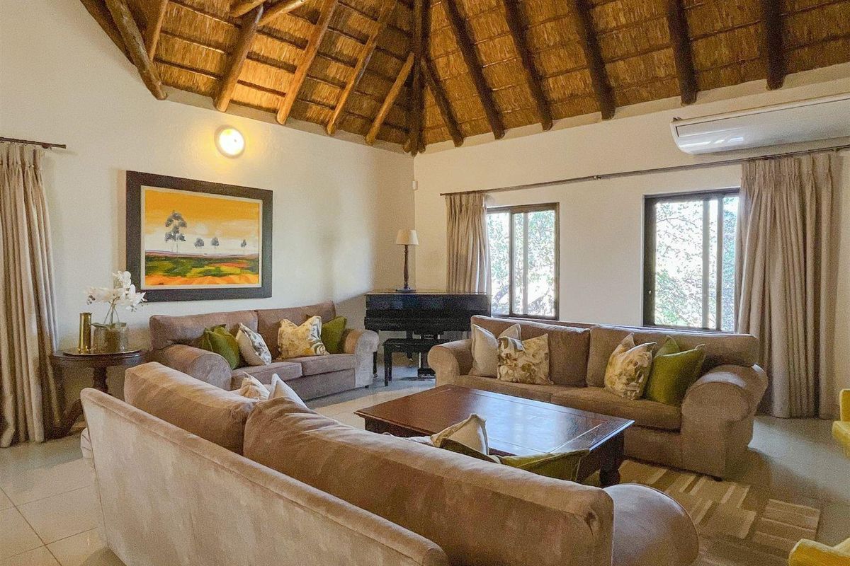 Spacious living room featuring a high vaulted thatched ceiling, tiled flooring, and a wall-mounted air conditioning unit.
