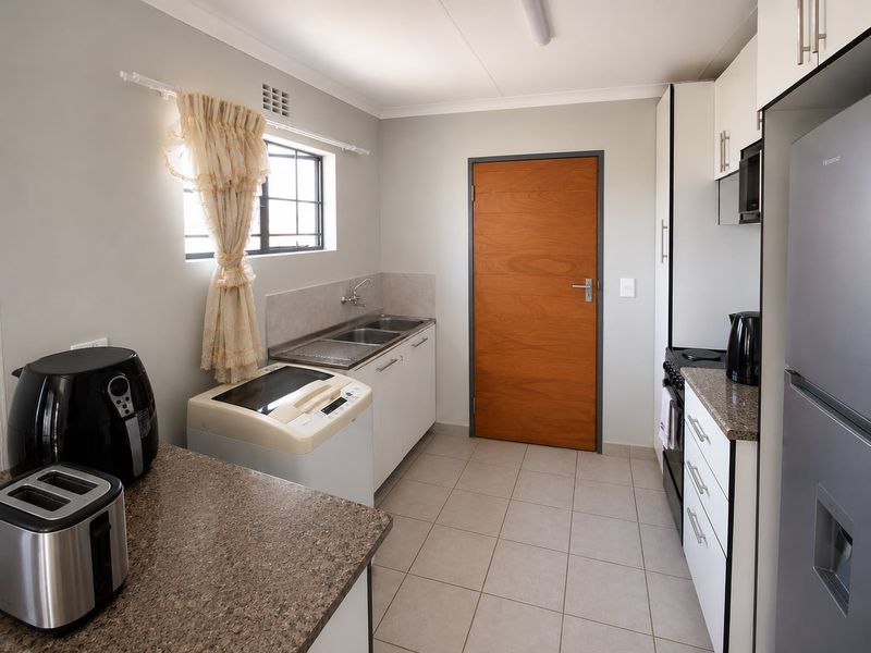 A functional kitchen featuring built-in cabinetry, laminate countertops, a double sink, and tiled flooring, providing a clean and practical workspace.