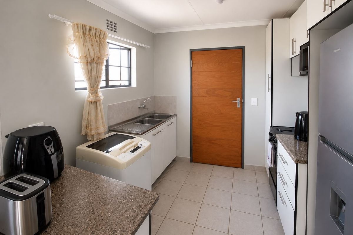 A functional kitchen featuring built-in cabinetry, laminate countertops, a double sink, and tiled flooring, providing a clean and practical workspace.