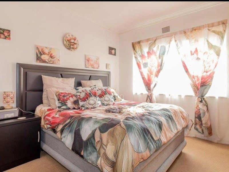 A standard bedroom featuring carpeted flooring and a ventilation grille, providing a functional and comfortable sleeping space.