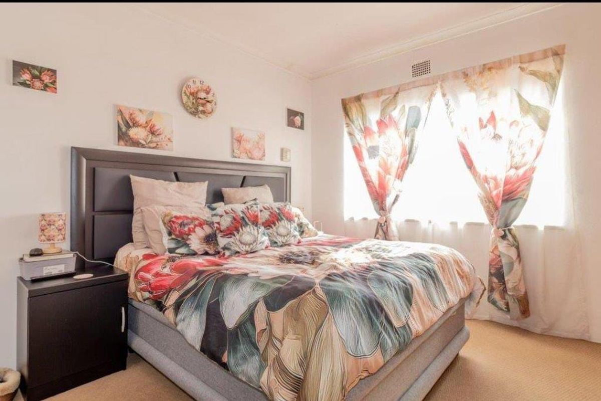 A standard bedroom featuring carpeted flooring and a ventilation grille, providing a functional and comfortable sleeping space.