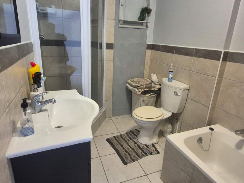 A functional bathroom featuring a vanity basin, a separate shower enclosure, a bathtub, and neutral wall and floor tiling.