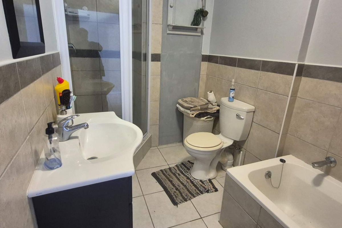 A functional bathroom featuring a vanity basin, a separate shower enclosure, a bathtub, and neutral wall and floor tiling.
