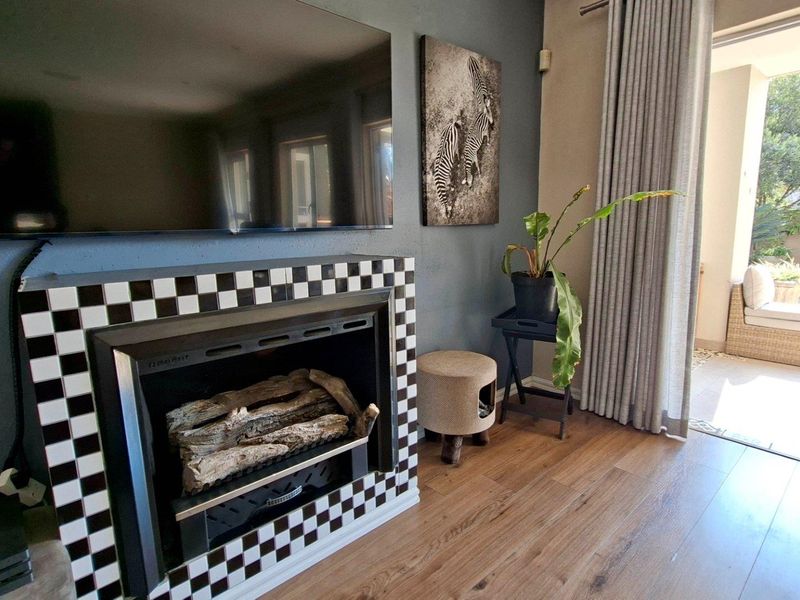 Living room featuring a built-in fireplace with a checkered tile surround, laminate flooring, and direct access to a patio and pool area.