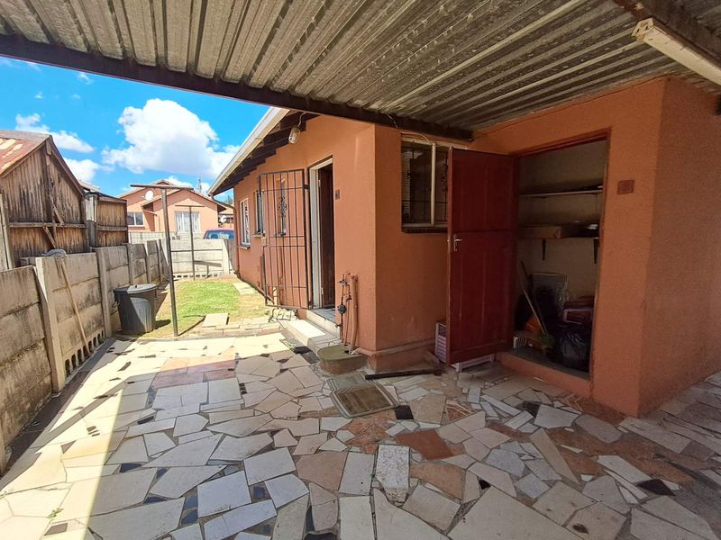 Covered patio area featuring crazy paving, a built-in storage alcove, and direct access to the rear garden space.