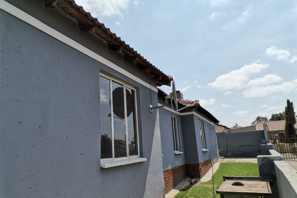 Exterior view of the house side elevation featuring tiled roofing, brick base detailing, and window installations.