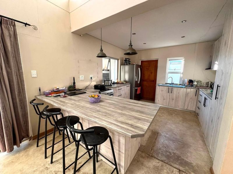 Open-plan kitchen featuring a large island with breakfast bar seating, wood-look cabinetry, and functional built-in appliances.
