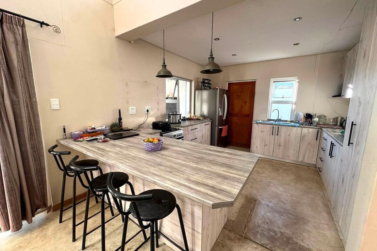 Open-plan kitchen featuring a large island with breakfast bar seating, wood-look cabinetry, and functional built-in appliances.