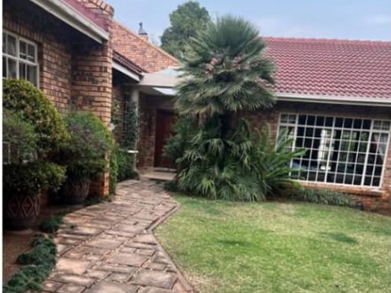A charming brick-faced home entrance featuring a stone-paved walkway, a well-maintained lawn, and a classic tiled roof design.