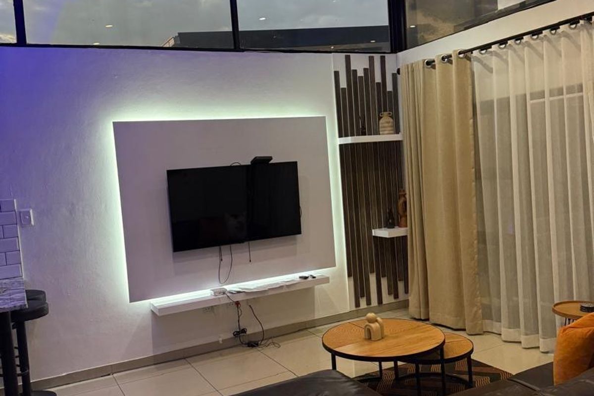 Modern living room featuring a built-in media wall with integrated LED lighting, high ceilings with clerestory windows, and large sliding doors leading outdoors.