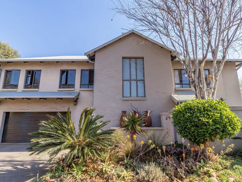 A well-maintained double-story residential home featuring a paved driveway, integrated garage, and established front garden with mature landscaping.