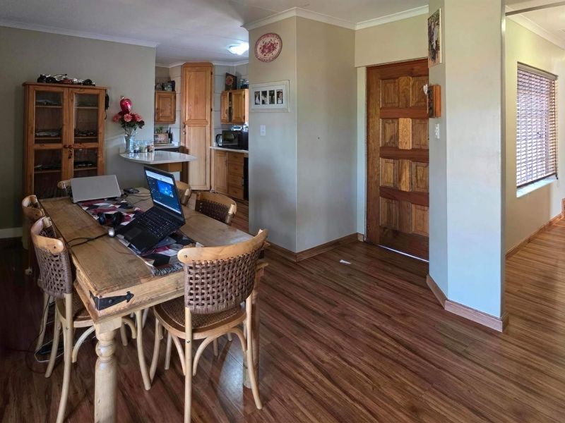 Open plan living and dining area featuring laminate flooring, wooden door, and access to a functional kitchen space with built-in cabinetry.