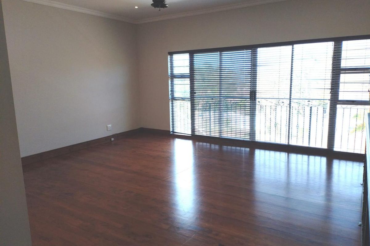 Spacious, empty bedroom featuring dark laminate flooring, a ceiling fan, recessed lighting, and large sliding glass doors with security bars and venetian blinds.
