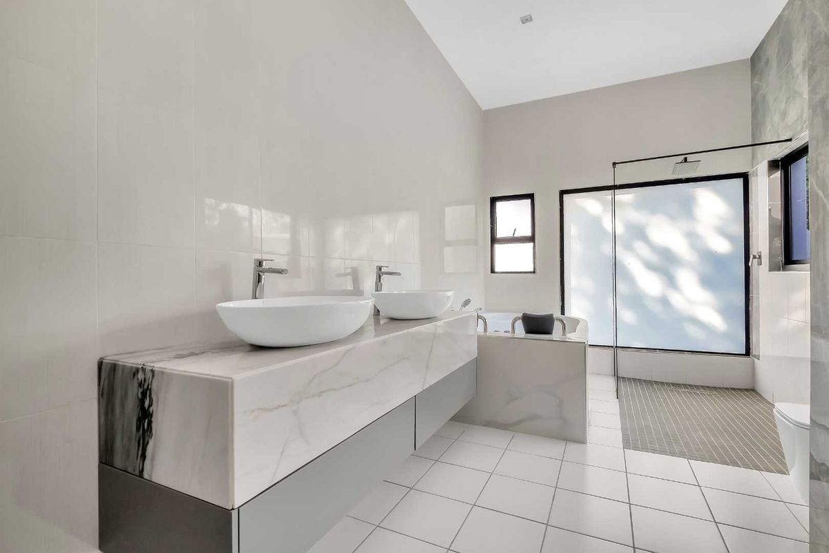 Modern bathroom featuring a double vanity with marble-look countertop, a walk-in shower with glass screen, and a separate bathtub.