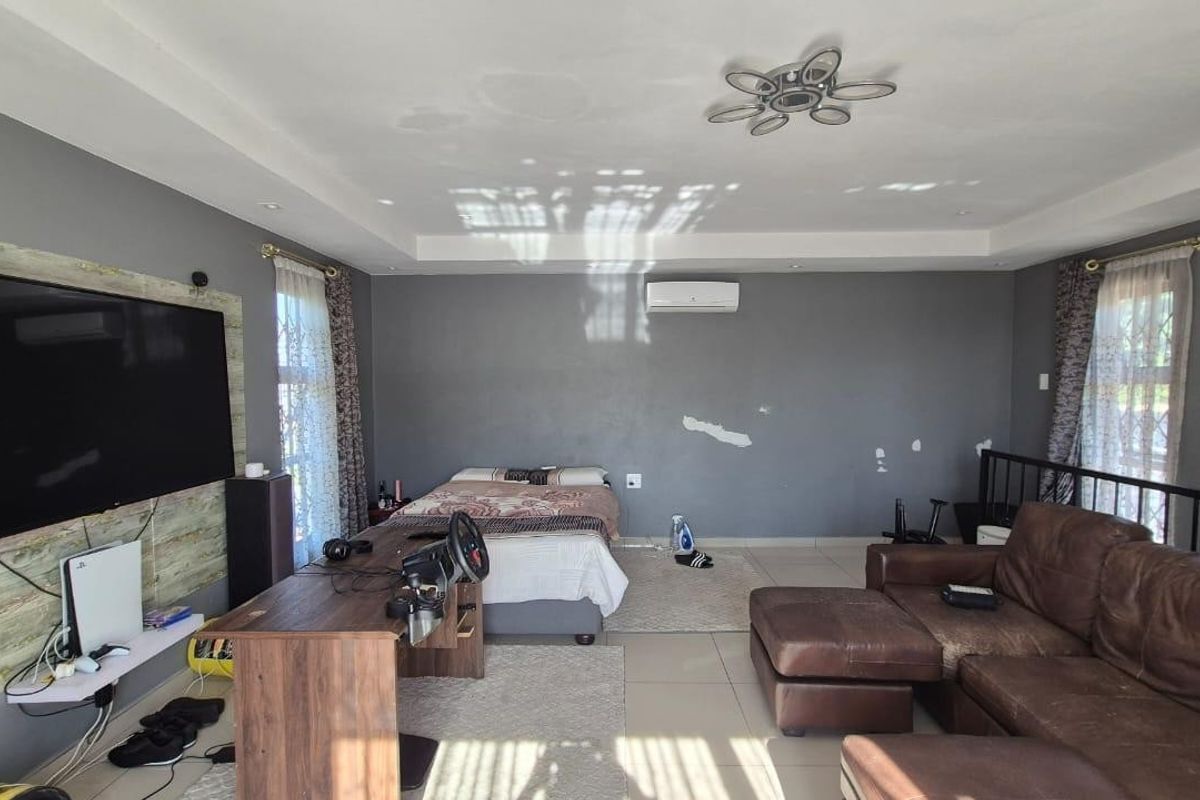 Spacious bedroom featuring tiled flooring, tray ceiling with recessed lighting, and an integrated air conditioning unit. Requires minor wall repairs and cosmetic updates.