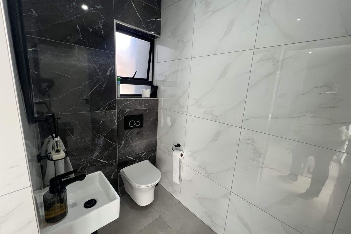 Modern guest bathroom featuring high-contrast black and white marble-look porcelain tiling, a wall-mounted toilet with concealed cistern, and a sleek wall-mounted basin.
