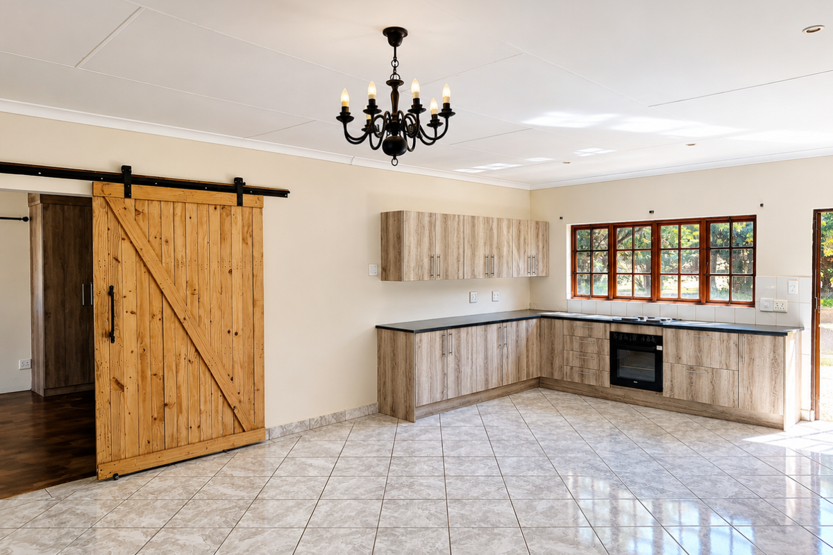 Spacious kitchen featuring light wood-finish cabinetry, dark countertops, built-in oven and hob, tiled flooring, and a distinctive sliding barn door.