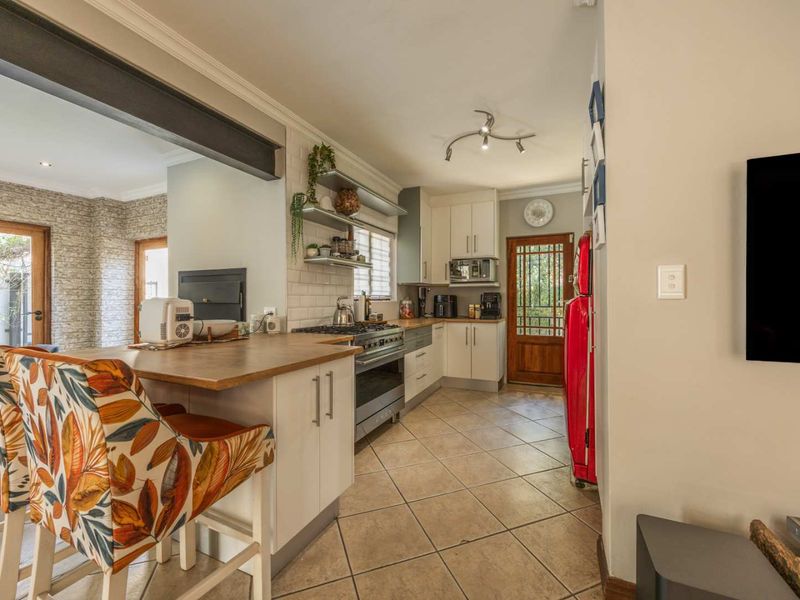 A well-appointed kitchen featuring a gas hob, subway tile backsplash, timber breakfast bar, and ample built-in cabinetry with tiled flooring.
