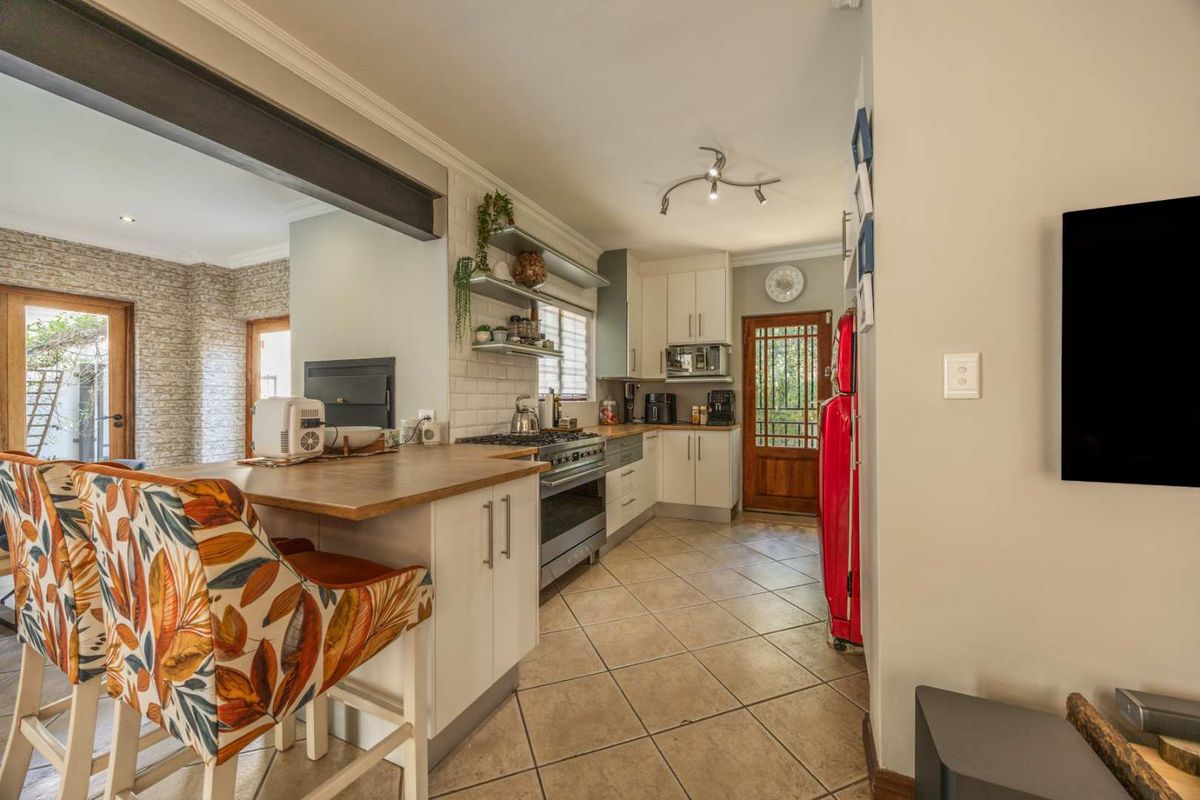 A well-appointed kitchen featuring a gas hob, subway tile backsplash, timber breakfast bar, and ample built-in cabinetry with tiled flooring.