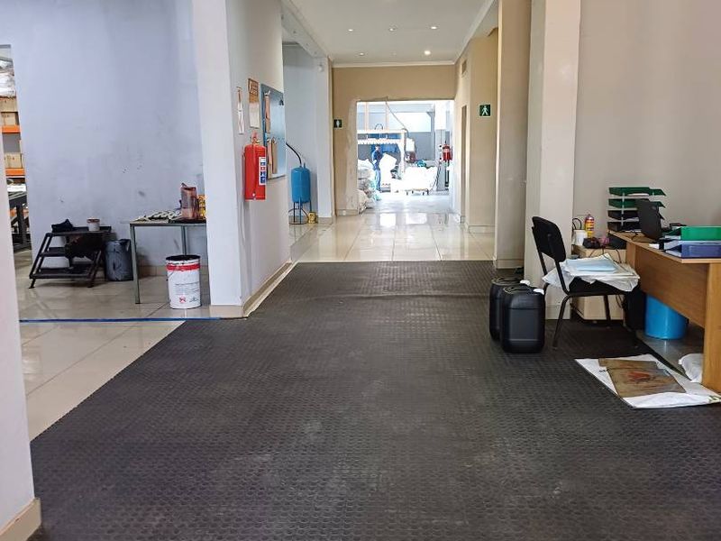 A functional retail or industrial hallway space featuring recessed ceiling lighting, tiled flooring, and a fire extinguisher.