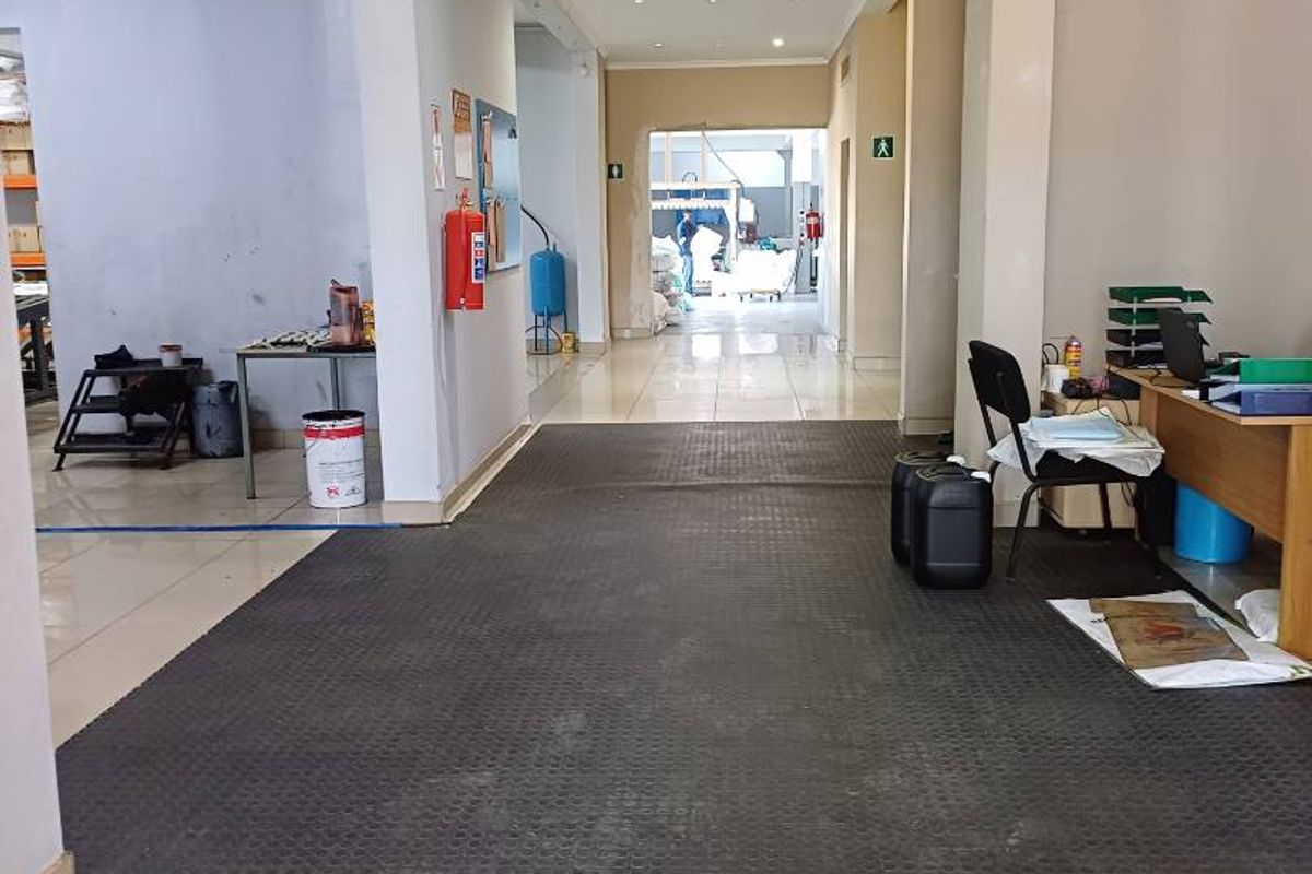 A functional retail or industrial hallway space featuring recessed ceiling lighting, tiled flooring, and a fire extinguisher.
