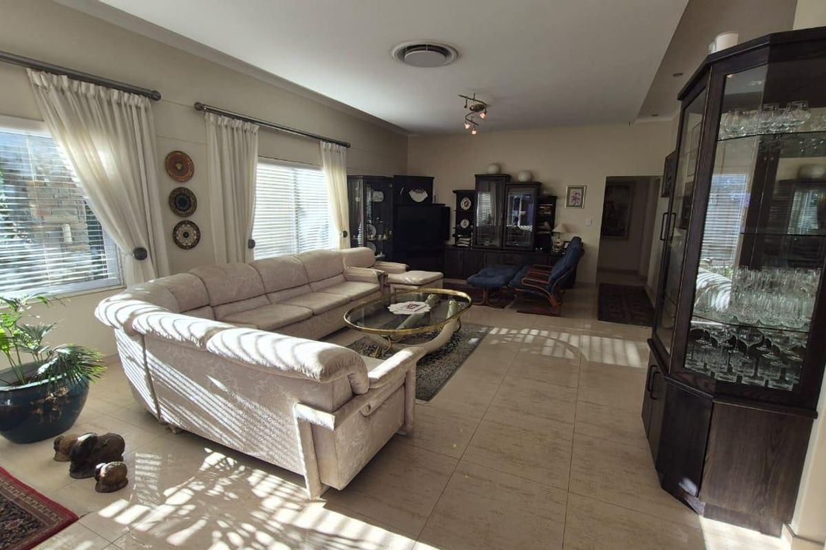 Spacious living room featuring large windows with blinds, tiled flooring, and recessed ceiling lighting.