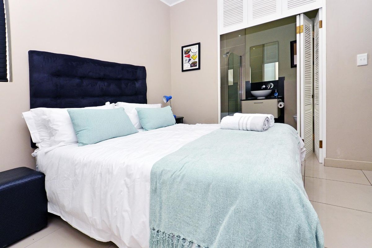 A well-maintained bedroom featuring tiled flooring and an en-suite bathroom with a modern vanity and glass shower enclosure.