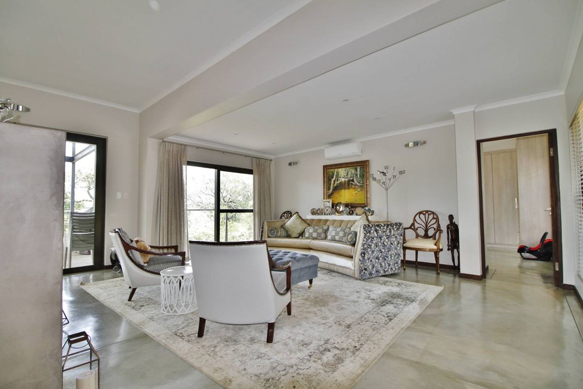 Spacious living area featuring polished concrete flooring, recessed downlighting, and large sliding glass doors providing access to the outdoor patio.