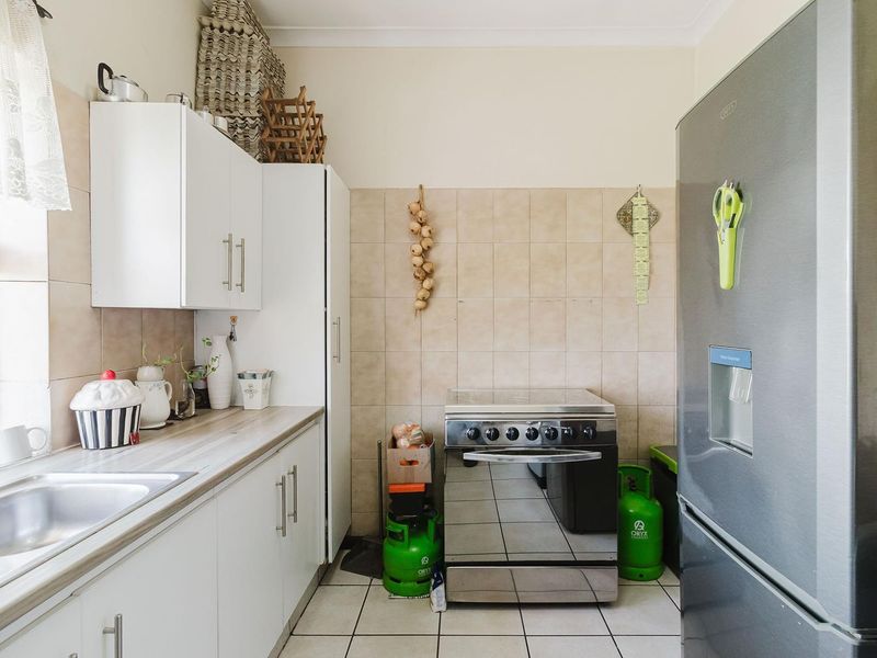 A functional kitchen featuring white cabinetry, tiled backsplash, laminate countertops, and a stainless steel sink, providing a practical workspace for daily cooking needs.