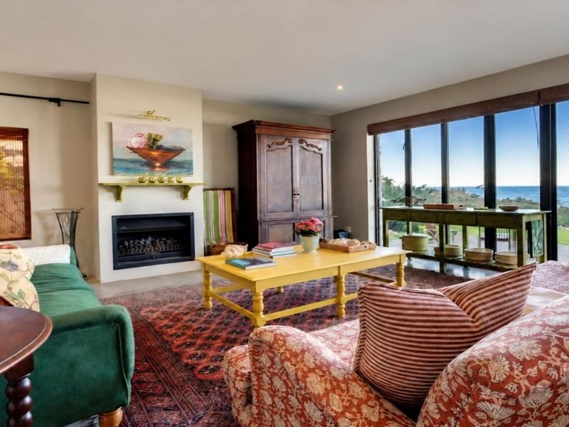 A comfortable living room featuring a fireplace and expansive floor-to-ceiling windows that offer stunning ocean views.