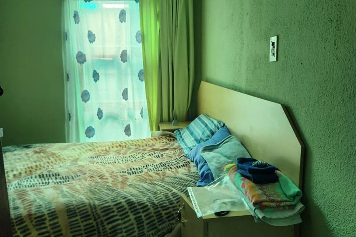 A bedroom featuring textured green walls, a window with curtains, and built-in headboard cabinetry.