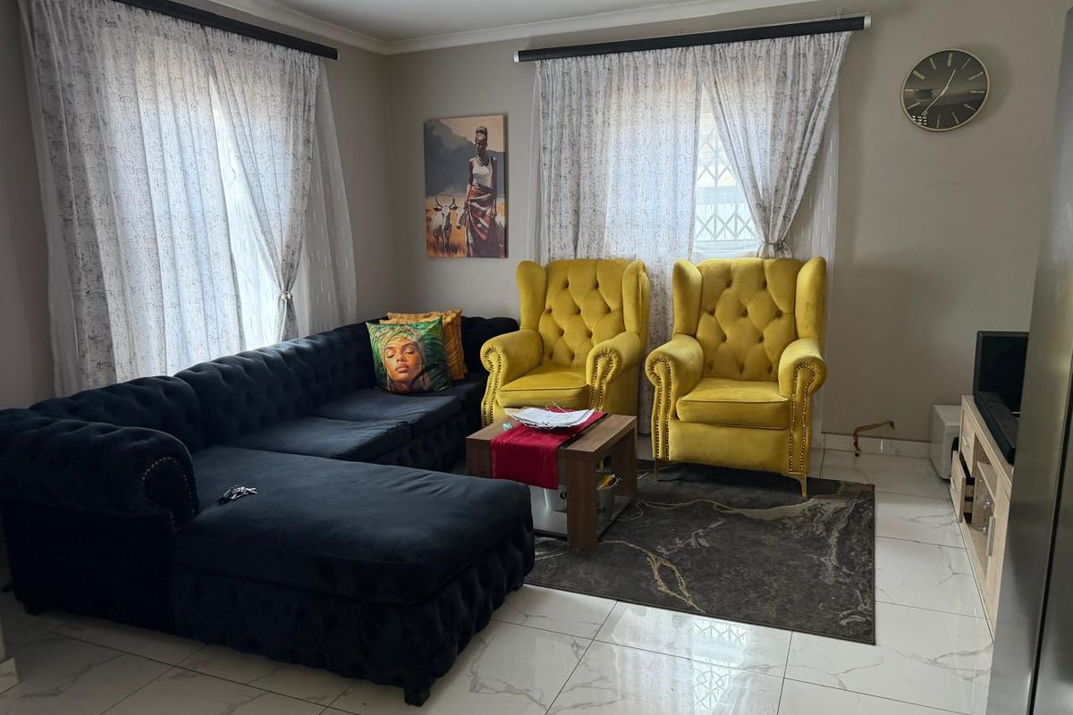 A well-maintained living room featuring polished tiled flooring and dual window treatments with curtain rails.