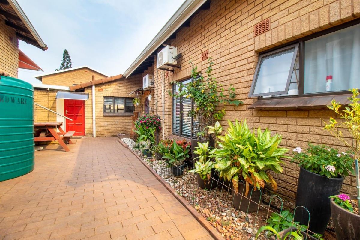 A well-maintained rear exterior area featuring a brick facade, paved walkway, and a large water storage tank.