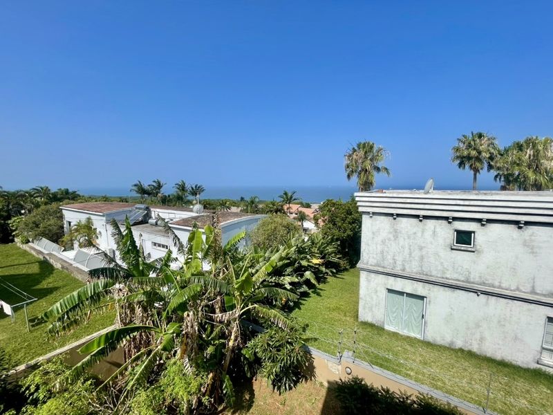 Elevated view overlooking the surrounding residential area with a distant ocean horizon and established garden greenery.