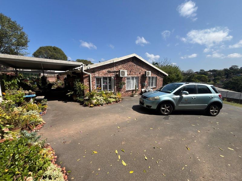 Front exterior view of a brick house featuring a paved driveway, attached carport, and security-fitted windows.